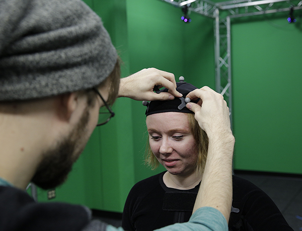 Andrew Fedie adjusts a reflector on the motion capture suit worn by Danielle Pedersen.