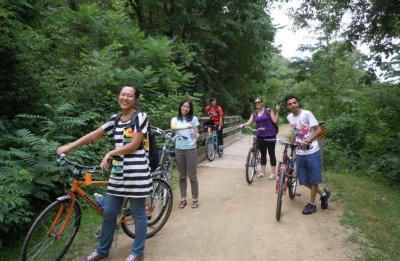 International students riding bikes in the woods on the Red Cedar trail