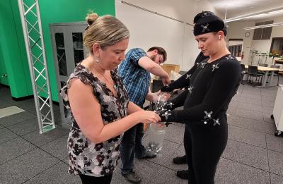 Amy Anderson places nodes on Kate Bratt's motion capture suit.